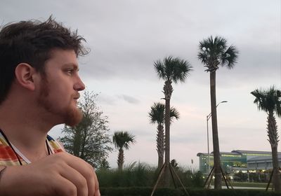 Portrait of young man looking away against sky