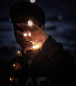 Close-up portrait of man holding illuminated candle
