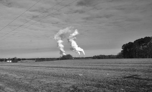 Smoke emitting from chimney on field against sky