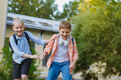Happy caucasian children running from school with backpacks on sunny day. begining of academic year.