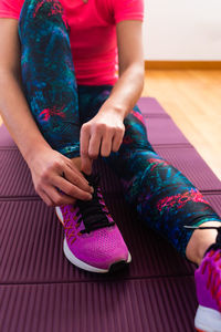 Low section of women sitting on pink at home