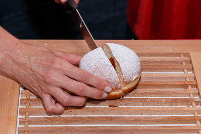 Cropped hands of person cutting bread on table
