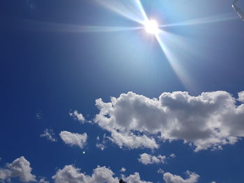 Low angle view of sunlight streaming through clouds