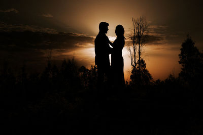 Rear view of silhouette woman standing against sky during sunset