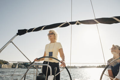 Woman on sailboat against sea against clear sky