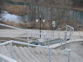 Concrete staircase with iron railings descending to the river in autumn