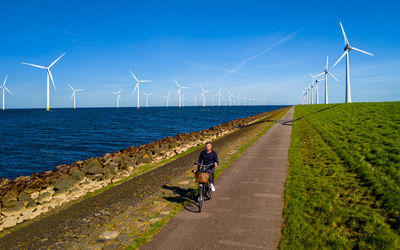 Rear view of man walking on road against sky