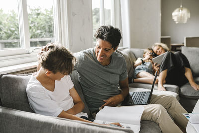 Friends using laptop while sitting on sofa at home