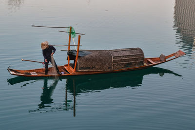 Reflection of man on boat in lake