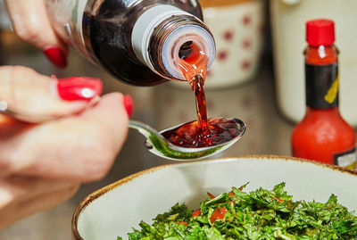 Chef pours pomegranate syrup with spoon to add to the salad.