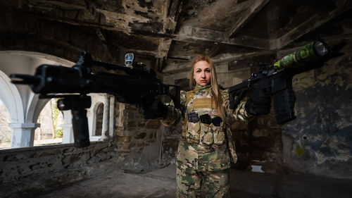 Portrait of young woman standing against wall