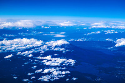 Aerial view of snowcapped mountains against blue sky