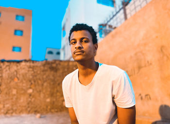Portrait of young man standing against building