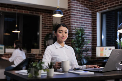 Businesswoman using laptop while standing in cafe