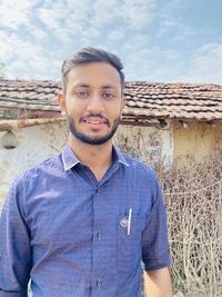 Portrait of young man standing against built structure