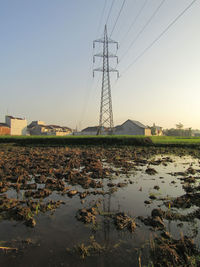 Electricity pylons on land against clear sky