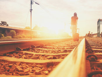 Surface level of railroad tracks against sky during sunset