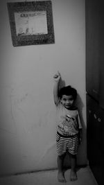 Portrait of girl standing against wall at home