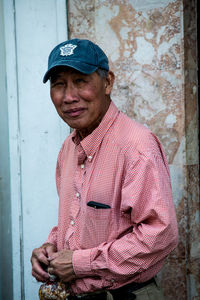 Portrait of smiling man standing against wall