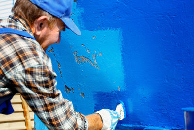 Midsection of man wearing hat against wall in city