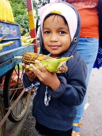 Portrait of smiling girl holding corn outdoors