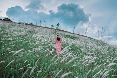 Rear view of woman standing on field against sky