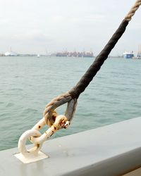 Rope tied to bollard at harbor against sky