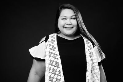 Portrait of woman standing against black background