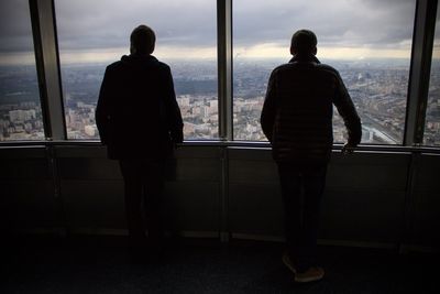 Rear view of two people looking through window