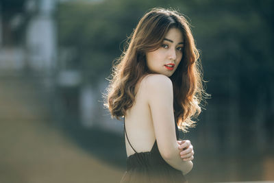 Portrait of beautiful woman standing against blurred background