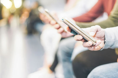 Cropped image of people using mobile phone outdoors