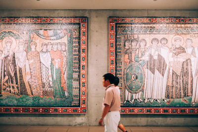 Rear view of woman standing by wall