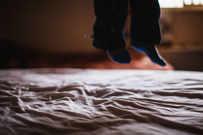 Low section of person jumping on bed