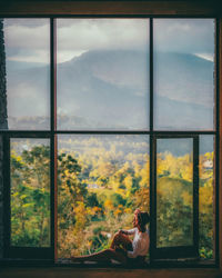 Side view of woman seen through window