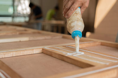 Close-up of hand pouring glue on wood