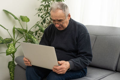 Young man using digital tablet while sitting on sofa at home