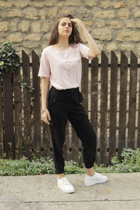 Portrait of teenage girl standing against stone wall