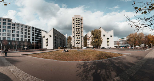 Road by buildings against sky in city