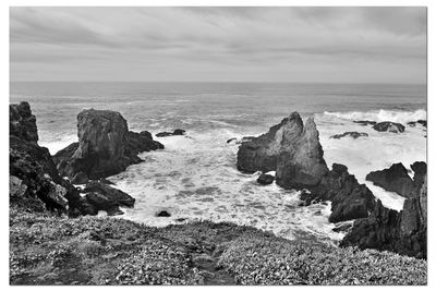 Rocks on sea shore against sky