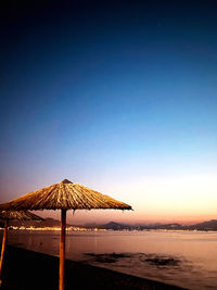 Lifeguard hut on beach against clear sky during sunset