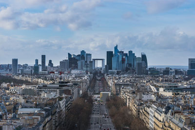 Aerial view of buildings in city against cloudy sky