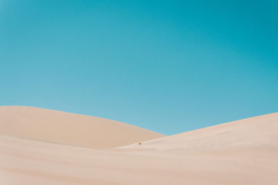 Sand dunes in desert against clear blue sky