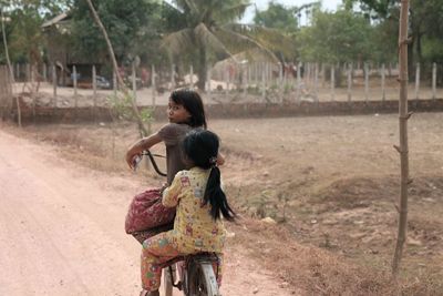 Rear view of mother with daughter standing on tree