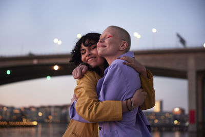 Happy young female friends or gay couple hugging each other