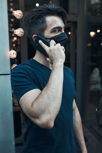 Young man wearing mask talking on phone outdoors