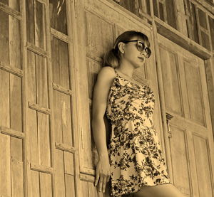 Low angle view of young woman standing against wall