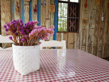 Purple flower vase on table against window