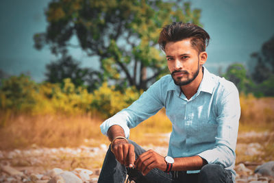 Portrait of young man sitting on land