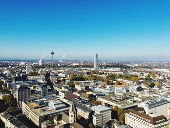 High angle view of buildings in city against clear blue sky