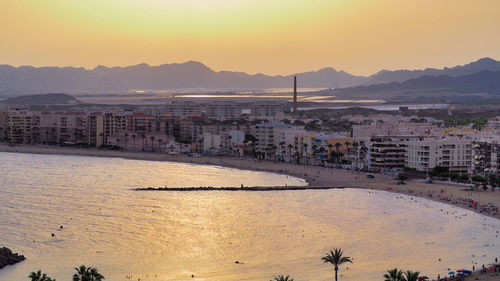 High angle view of buildings by sea against clear sky during sunset